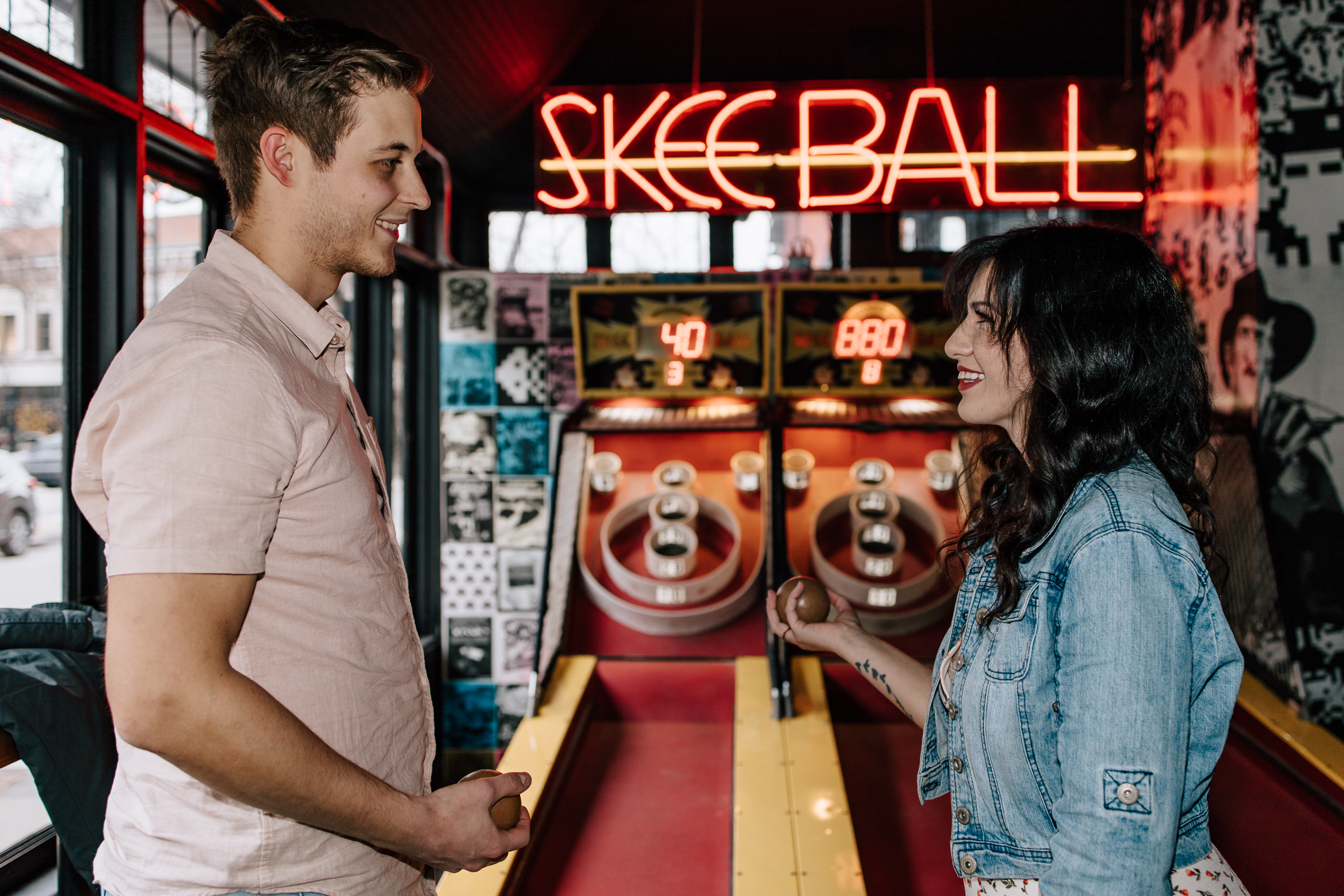 An engaged couple look at each other holding skeeballs while playing skeeball at Up-Down Arcade in St. Louis, Missouri.