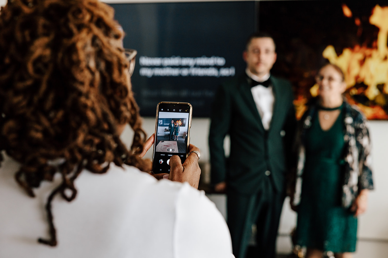 A guest takes a photo of the groom and his mother before his micro-wedding elopement ceremony at White Box Studio / Fathom STL in St. Louis, Missouri.