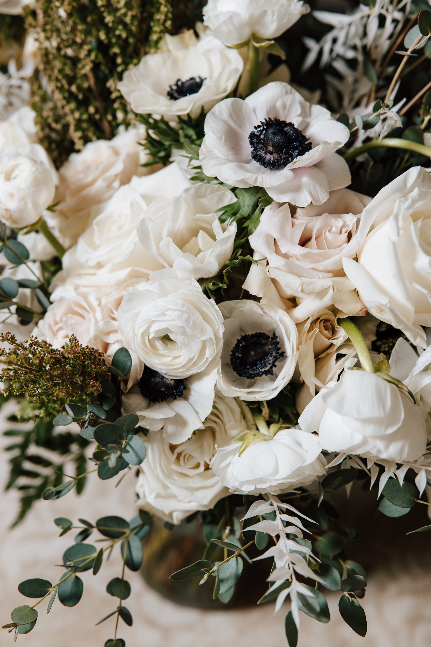 Peonies, ranunculus, white roses, and greenery make up the bride's bouquet.