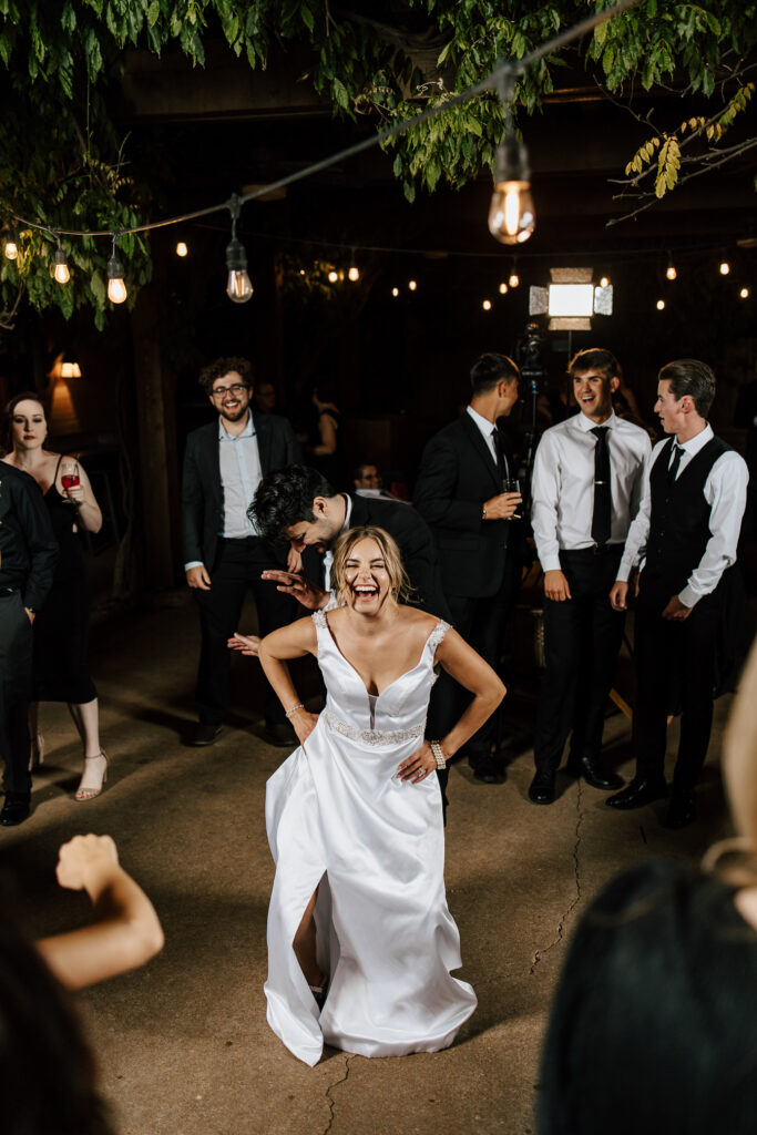 A bride and groom happily dance on their dance floor surrounded by guests.